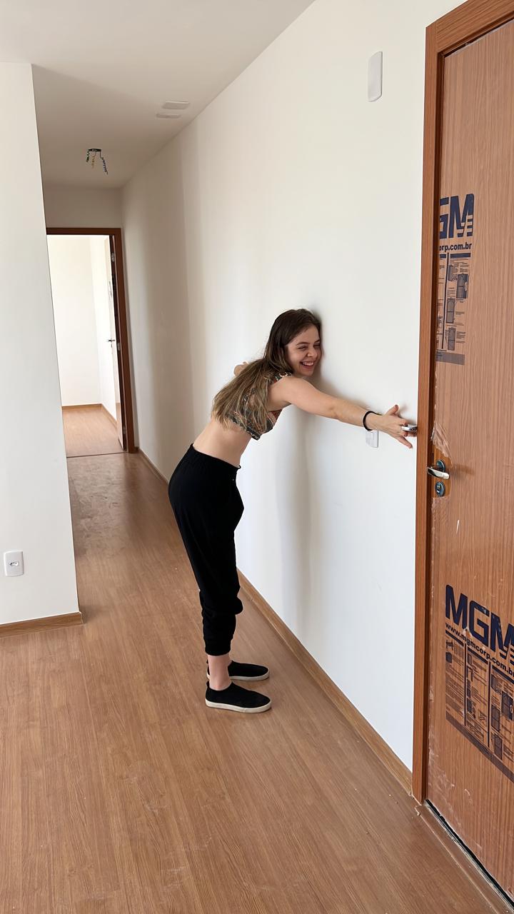 Vitória abraçando a parede ao lado da porta do novo apartamento