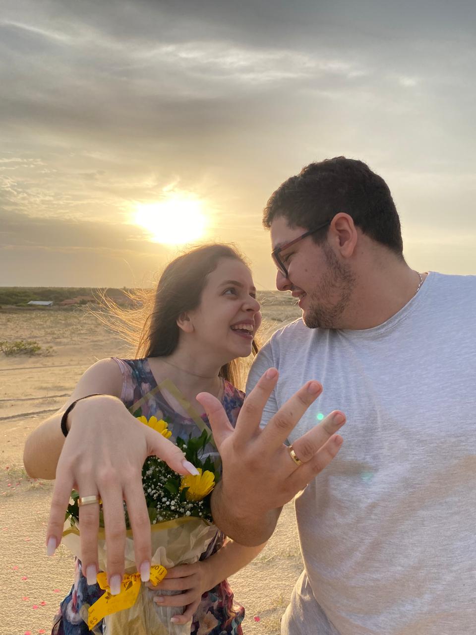 Os dois mostrando suas alianças ao pôr do sol